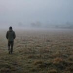 Solitary figure walking through a misty field at dawn, for alone quotes