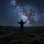 Silhouette of a person on a hilltop gazing at a starry night sky, for dream big quotes